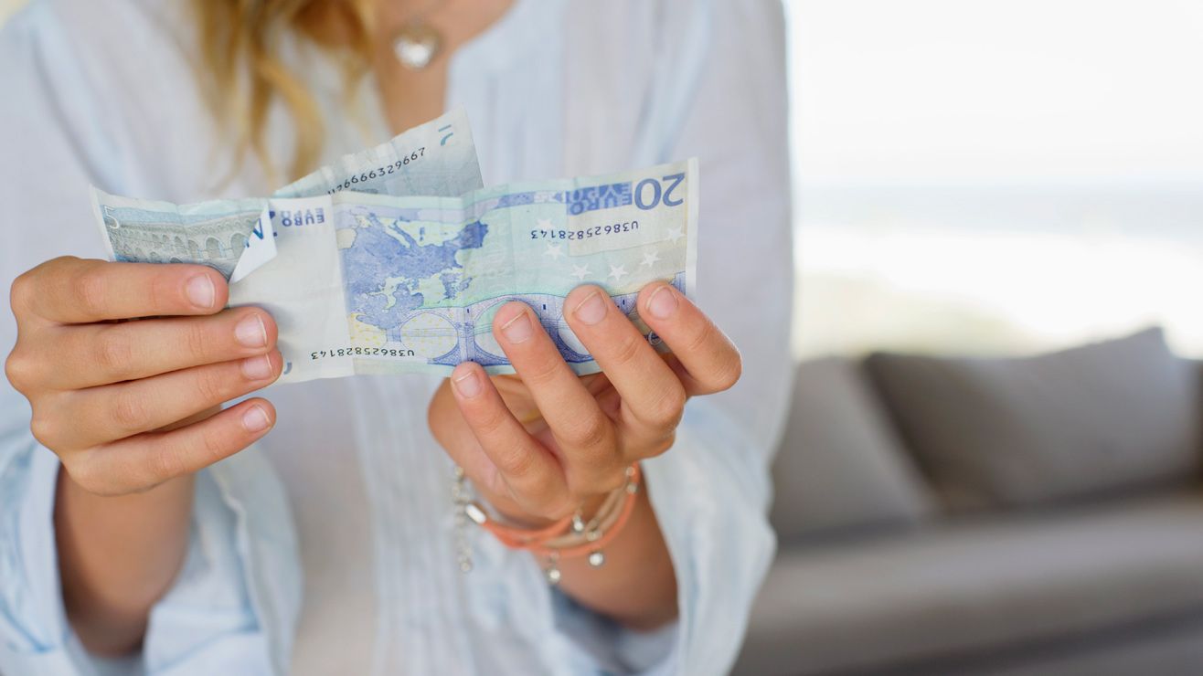 A woman holding two Euro notes
